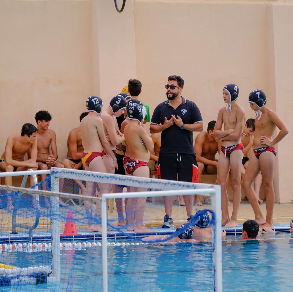 Entrenador dando instrucciones al equipo junto a la portería