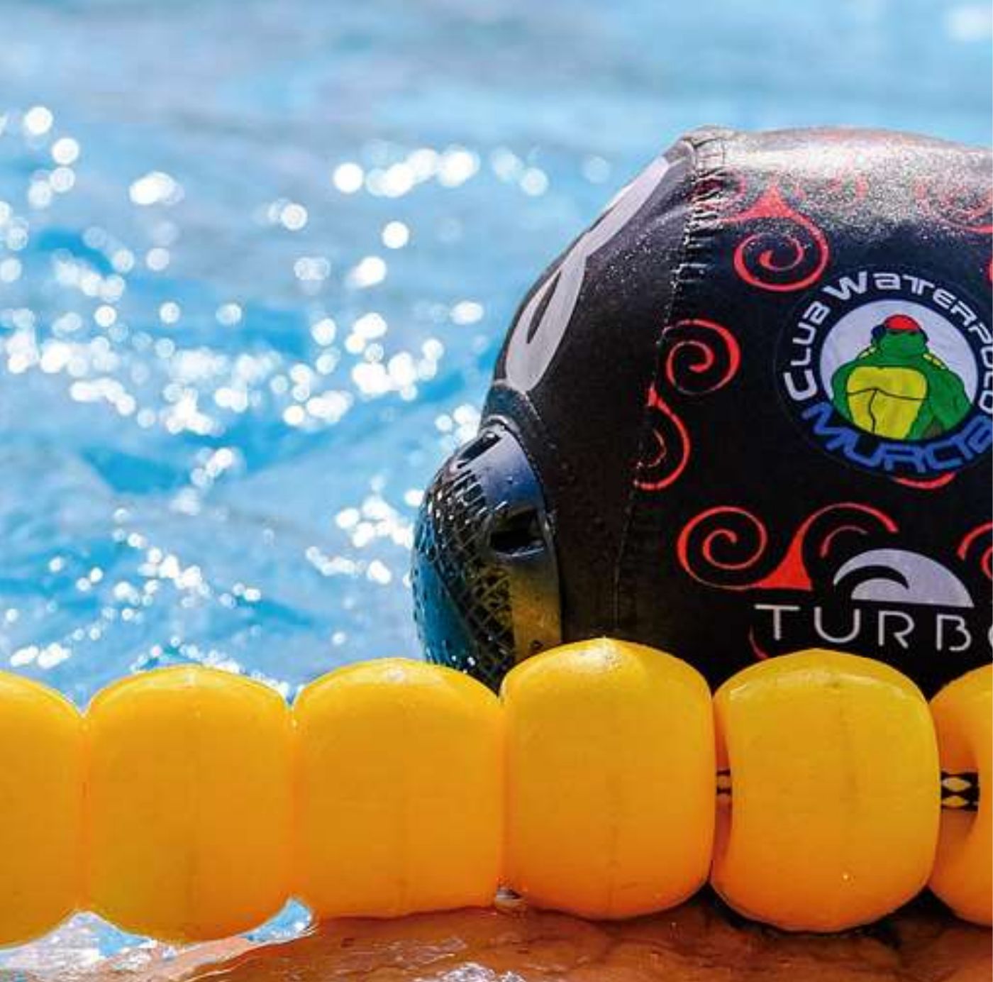 Gorro del Club Waterpolo Murcia apoyado en una corchera amarilla
